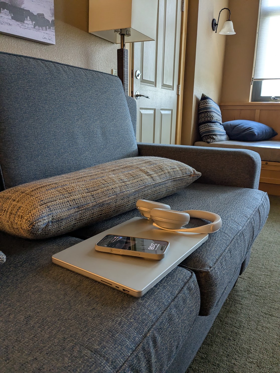an iphone, macbook, and headphones on a couch