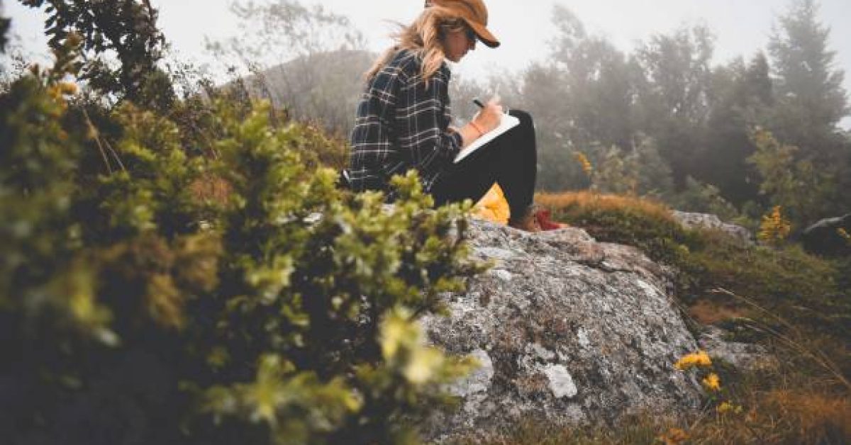 woman journaling in the woods